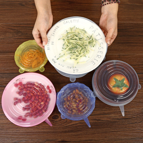 Colorful silicone lids on bowls with food on a wooden surface