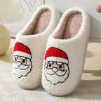 Pair of white slippers with Santa Claus face design on a soft surface.